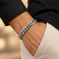 Polished curb-link bracelet worn on a wrist with an ivory linen sleeve