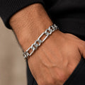 Polished alternating elongated rectangular links and shorter rounded curb links, lobster clasp. Worn on an adult wrist with ivory linen