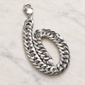 Polished flat curb-link chain with lobster clasp. On an ivory background