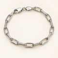 Alternating open and textured elongated links bracelet on an ivory background