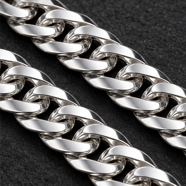 Polished flat curb-link chain with lobster clasp. Macro view of visible bracelet details
