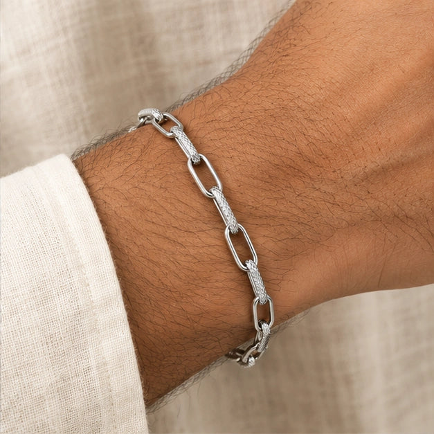 Alternating open and textured elongated links bracelet worn on an adult wrist beside ivory linen