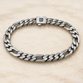 Flat alternating curb and elongated link bracelet on an ivory background