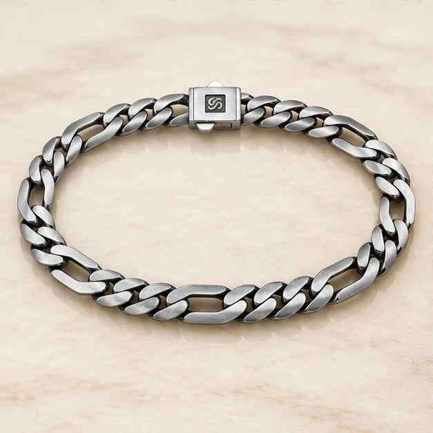 Flat alternating curb and elongated link bracelet on an ivory background